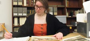 Photograph of curator Beck Moraski '21 sitting at a table in Special Collections reading room.