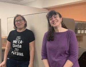 Maria Gorbunova and Amy Graham in the Special Collections office, smiling. Maria wears a t-shrt printed "No Meta-Data No Future."