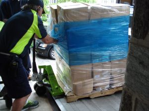 Delivery worker dragging a pallet of 45 large boxes onto a dolly