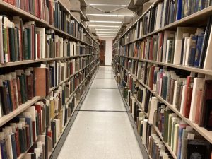 One densely packed aisle of the EY Wood Collection in the library stacks.